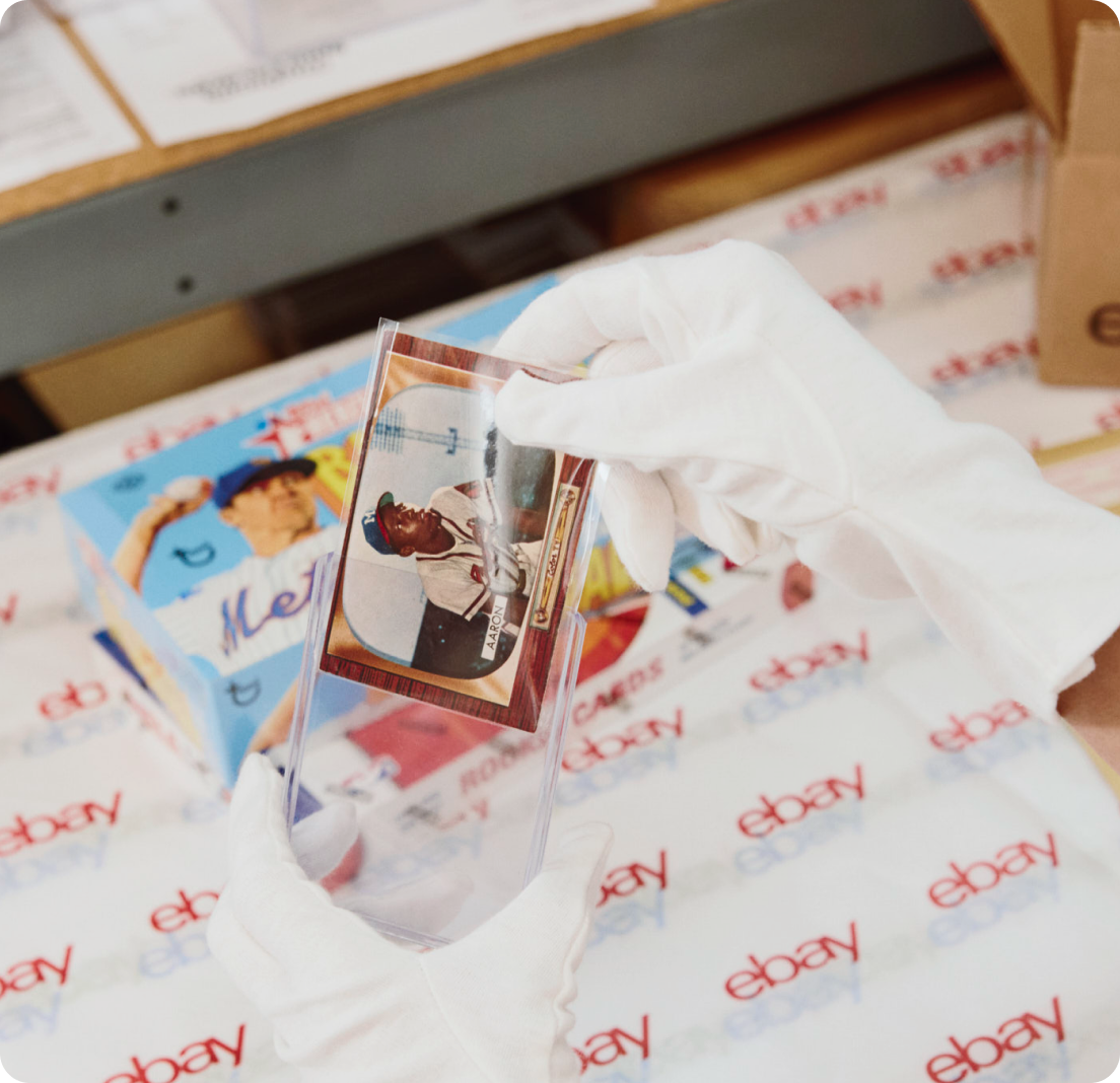 A gloved hand placing a baseball card into a protective sleeve